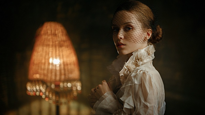 Woman in veil and ruffled shirt near lamp