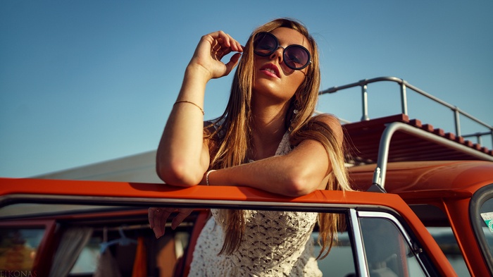 Woman with sunglasses leaning on a car