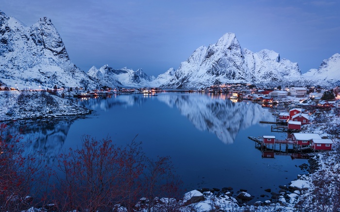 Snowy mountains and village reflected in water in Norway