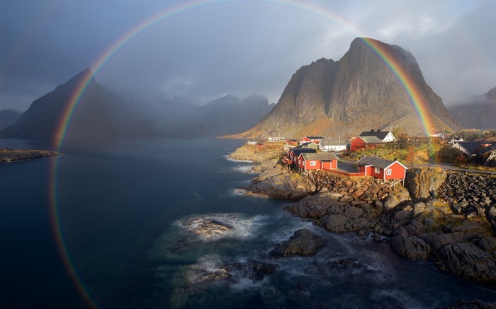 Rainbow over a Norwegian village with mountains and sea