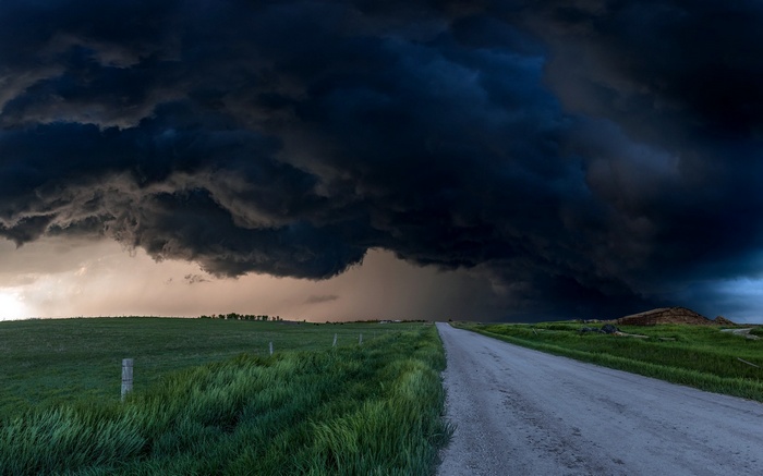 Storm clouds over a rural landscape with a dirt road