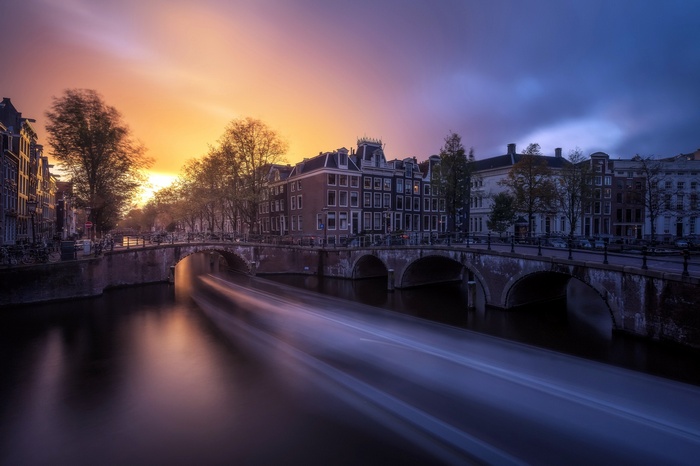 Amsterdam cityscape with canal and bridge at sunset