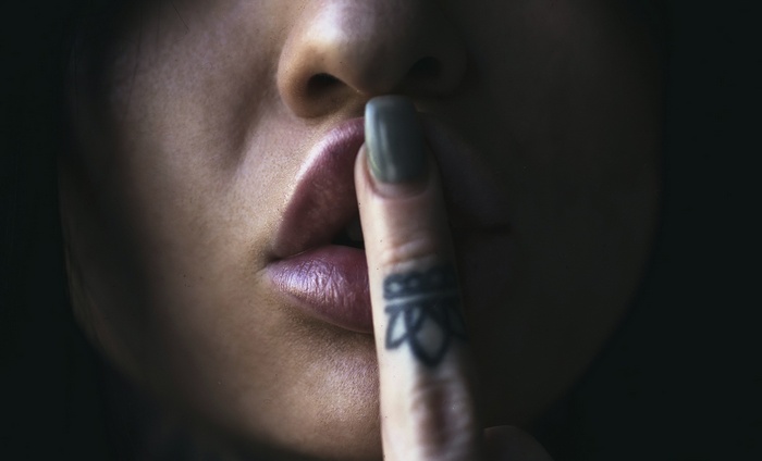 Woman with finger on lips and tattoo