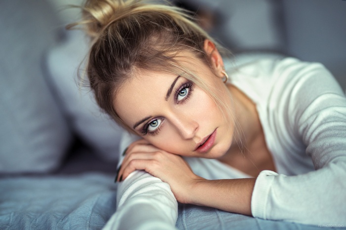 Woman with blonde hair in a bun lying down