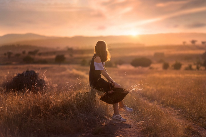 Woman sitting in a field at sunset