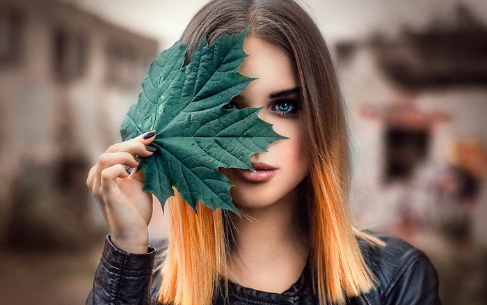 Woman with blue eyes holding a green leaf
