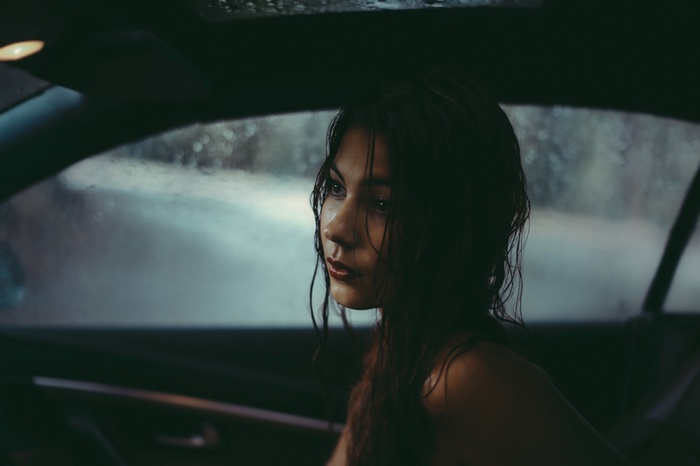 Woman with wet hair in a car during rain