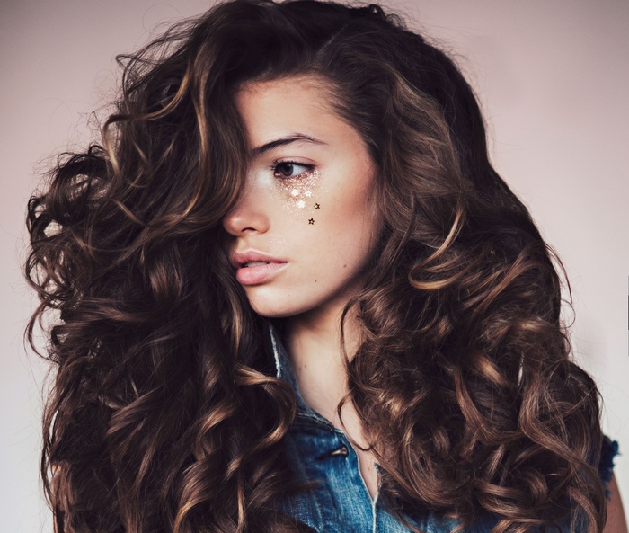 Woman with curly hair and glitter on face