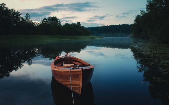 Wooden rowboat on a calm lake at dusk