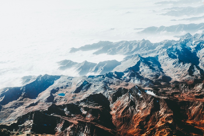 Aerial view of snow-capped mountains above clouds