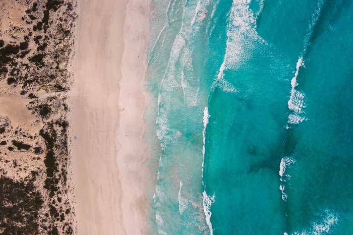 Aerial view of a sandy beach with turquoise ocean waves