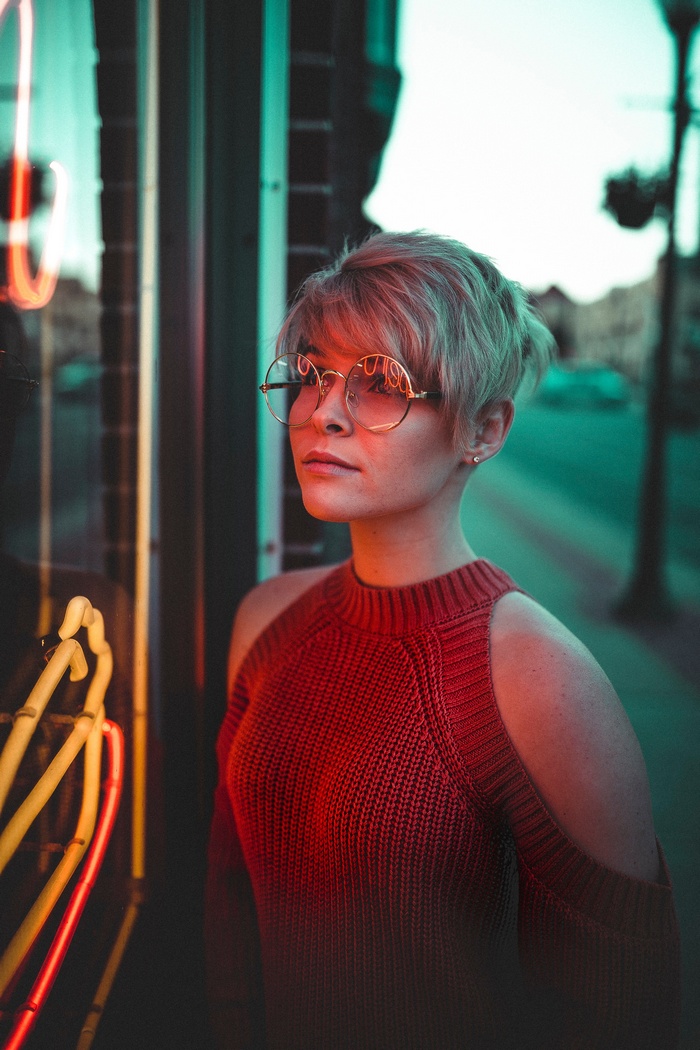 Woman with short hair and glasses near neon lights