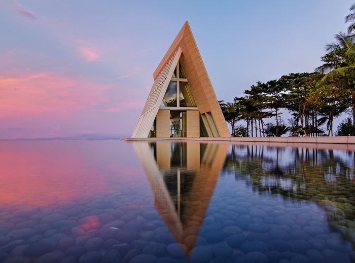 Modern chapel reflected in water at sunset