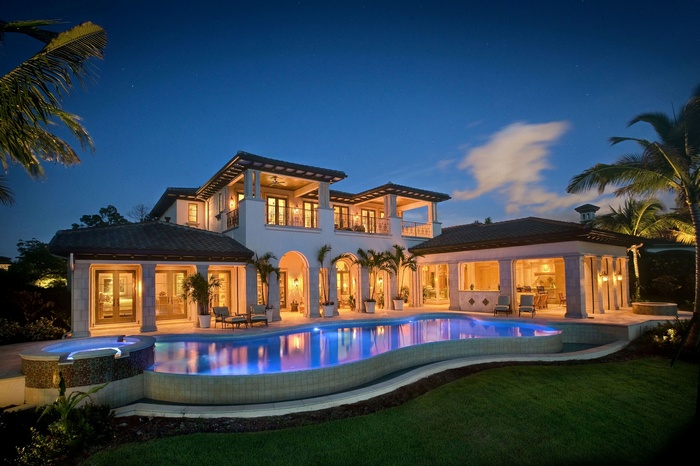 Modern house with swimming pool and palm trees at night