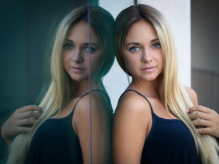 Woman with blonde hair and green eyes reflected in glass