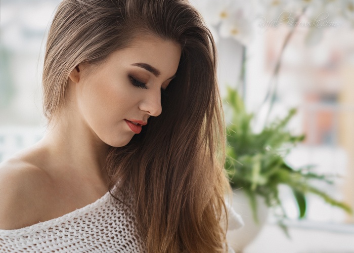 Woman with long brown hair wearing a white sweater