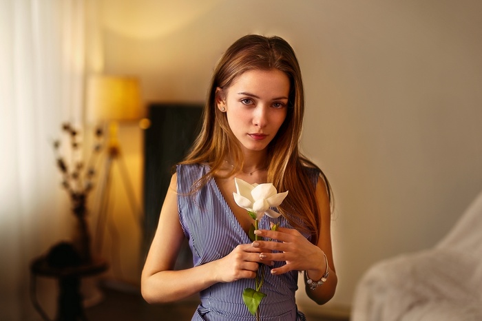Woman holding a white flower indoors