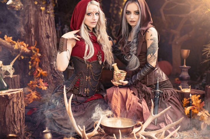 Two women dressed as witches in a forest setting