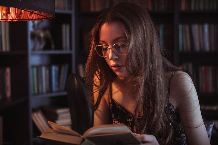 Woman with glasses reading a book in a library