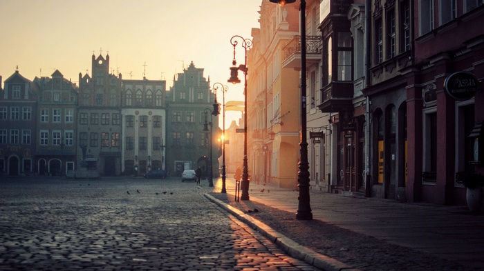 Old European city square at sunrise with cobblestone street