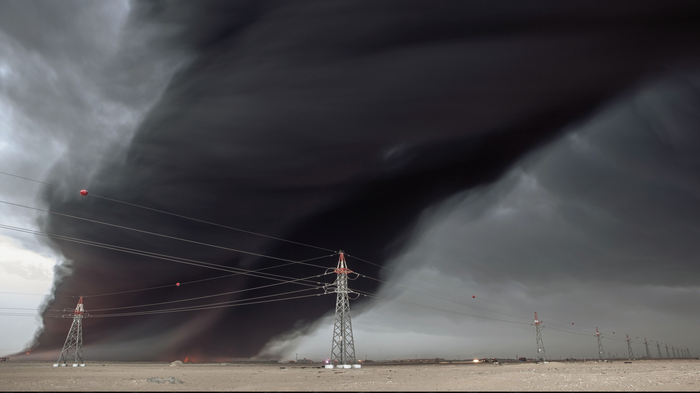 Tornado over desert with power lines and fire