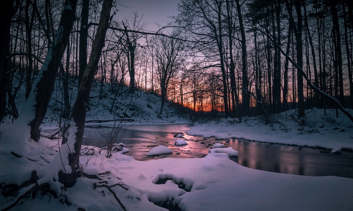 Winter forest stream at sunset with snow