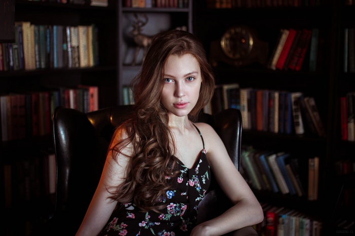 Portrait of a young woman with long brown hair in a library