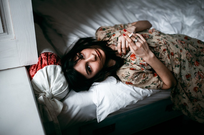 Woman lying on bed smoking a cigarette