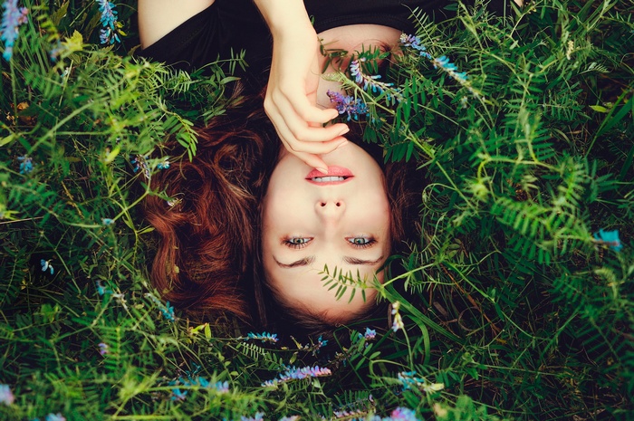 Woman lying in grass with flowers, finger on lips