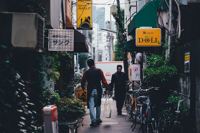 Two men walking down a narrow street in Japan