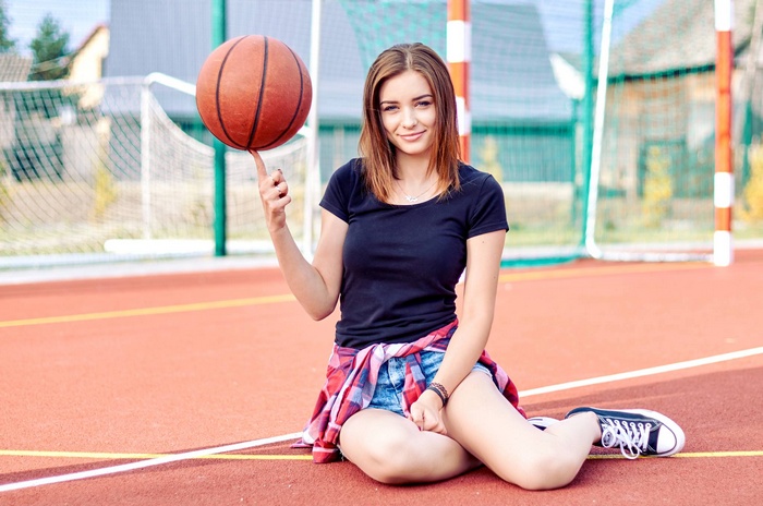 looking at viewer, model, short hair, smiling, women, black tops, women outdoors, sitting, jean shorts, brunette, sneakers, ball, straight hair