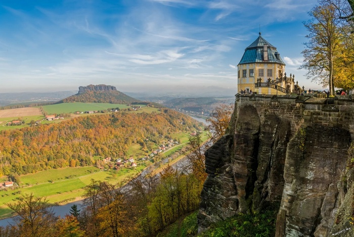 Castle on a cliff overlooking a valley and river in fall