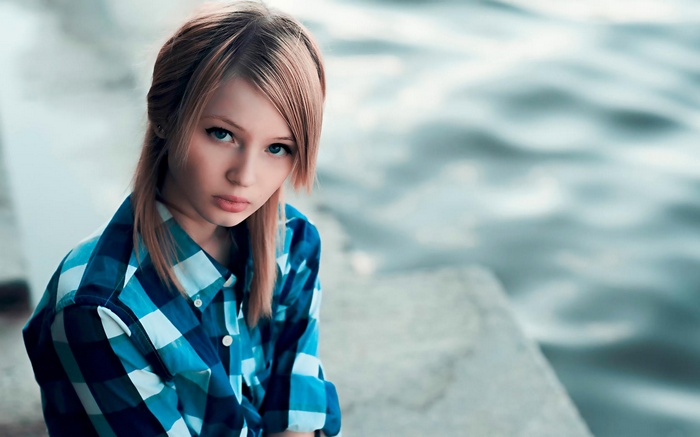 Young woman with blonde hair and blue eyes wearing a blue plaid shirt