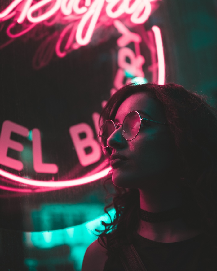 Woman with glasses in front of neon sign in Boston