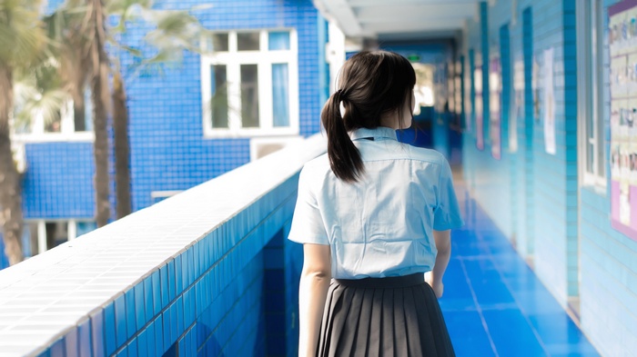 Asian girl with black hair in a ponytail wearing a school uniform