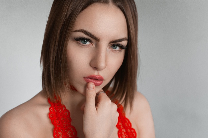 Woman with red lipstick and finger on lips