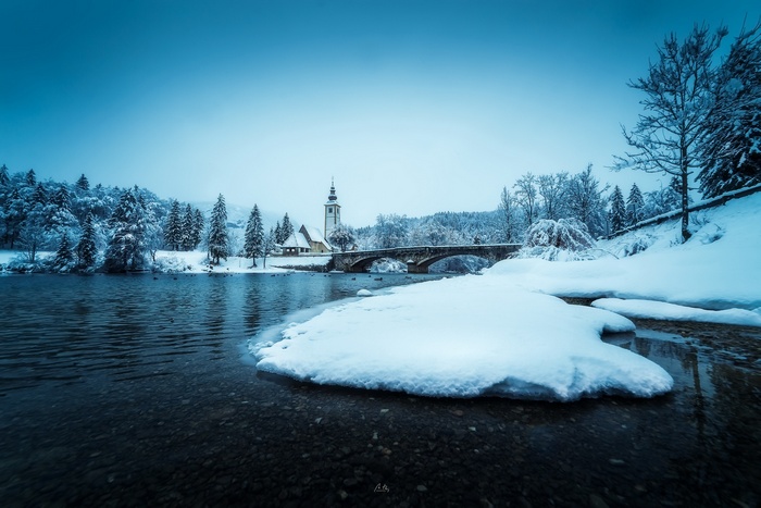 Winter landscape with a bridge and church in Slovenia