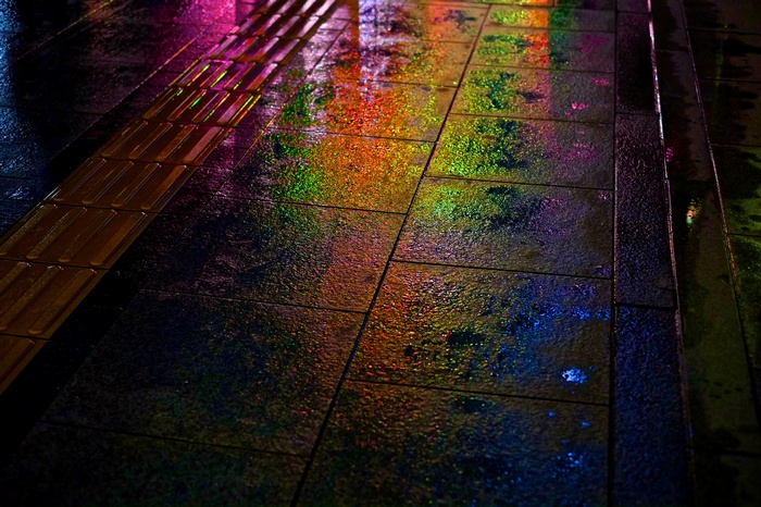 Colorful reflections on a wet sidewalk at night