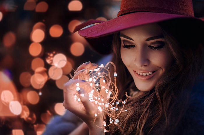 Woman in hat holding string lights