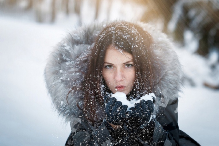 Woman in winter jacket blowing snow