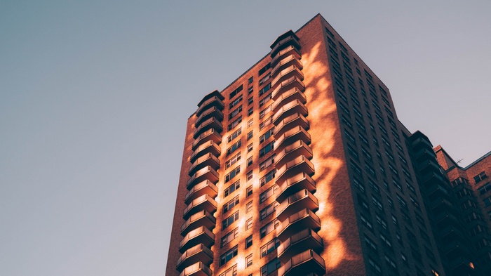 Tall brick building with balconies against a clear sky