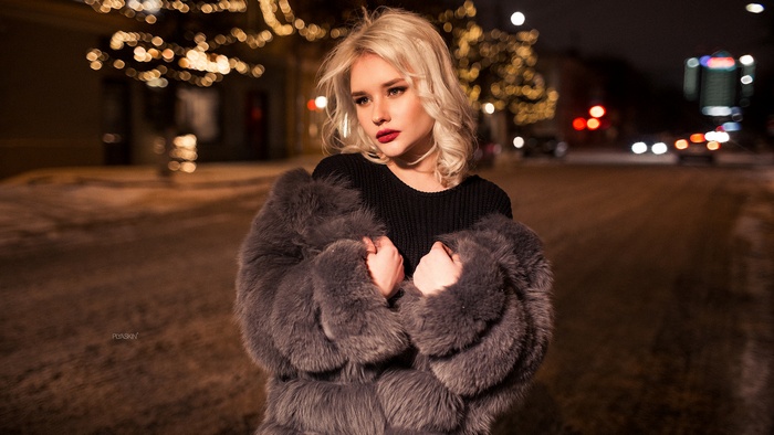 Woman in fur coat on a bokeh street at night