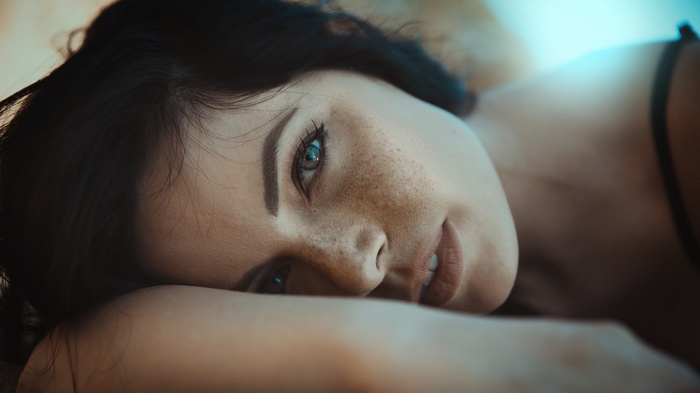 Woman with freckles and dark hair lying down
