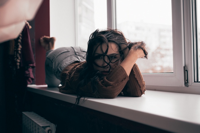 Woman with hair in face lying on window sill