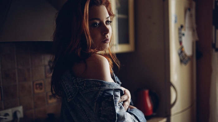 Woman with red hair in a denim jacket in a kitchen
