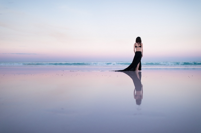Woman in black dress on a beach at sunset