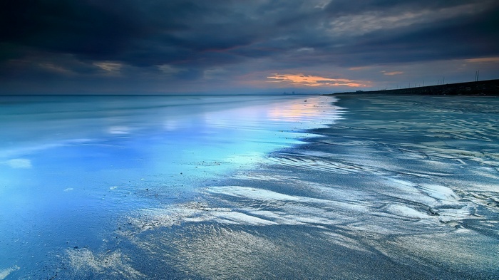 Beach with calm ocean and dramatic sky