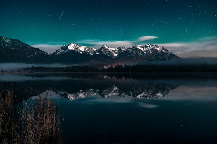 Mountains reflected in a lake under a starry sky