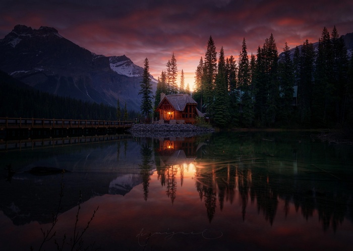 Cabin by a lake with mountains at sunset