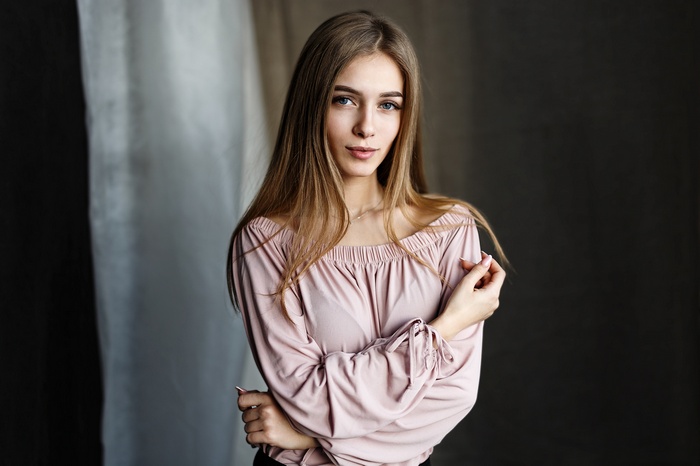 Woman with long blonde hair wearing a pink off-the-shoulder top